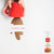 A hand holding a red cup with a brown coffee stain marks, symbolizing a casual and discreet beverage container along with the vooki spray and wipe bottle at the corner.